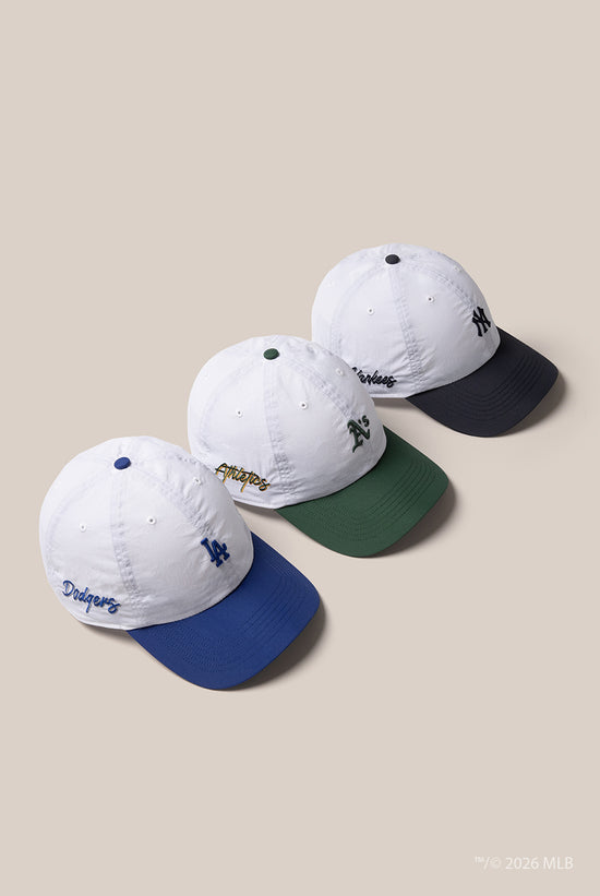 Slide 2:3 '47 brrr technology caps in a row, one with a blue peak and small LA logo, one with a green peak and small A's logo and one with a navy peak and small NY logo 